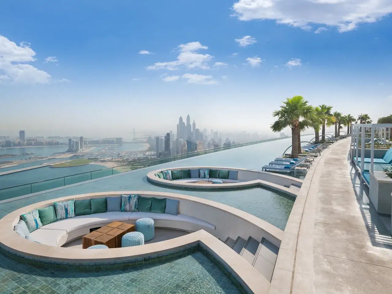 Luksusowy basen infinity z widokiem na Dubaj. Idealne miejsce na wymarzone dubaj wczasy, relaks wśród palm i miejskiego krajobrazu.