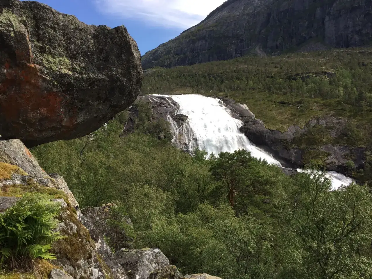 Vandring Hardangervidda: en mäktig forsande vattenfall omgiven av grönskande skog och dramatiska berg.