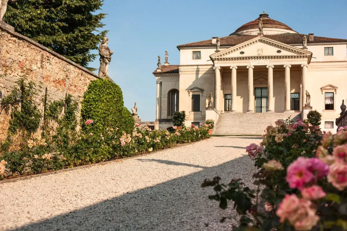 Un sentiero ghiaioso conduce a una villa palladiana, circondata da un giardino fiorito. Un luogo incantevole tra le ville da visitare.