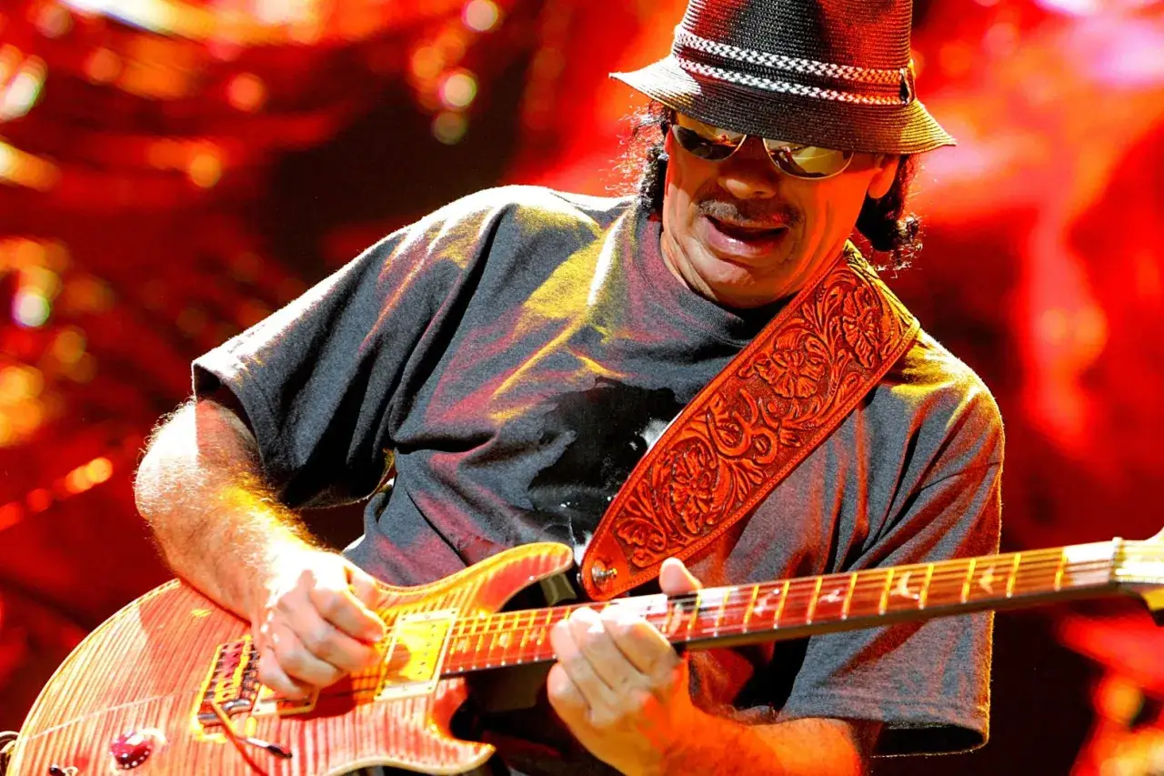 Carlos Santana w kapeluszu i okularach gra na gitarze, wykonując najbardziej znany utwór.