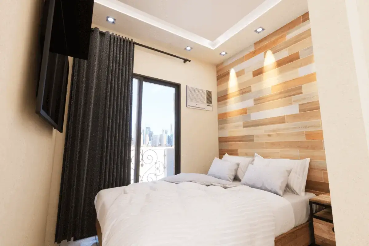 Camera da letto singola con letto matrimoniale, TV a muro, finestra con vista panoramica e parete in legno.