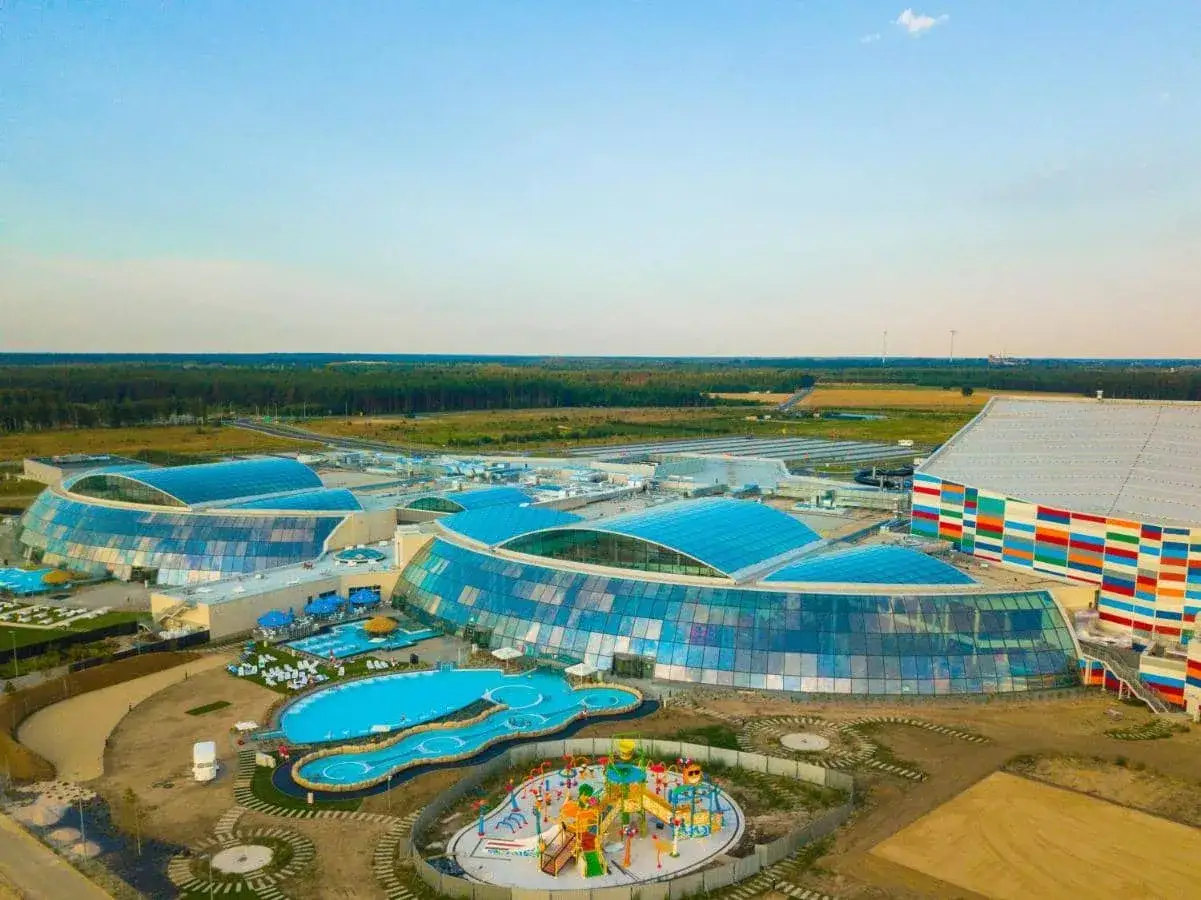 Nowoczesny kompleks z basenami i zjeżdżalniami, największy park wodny w Europie, otoczony zielenią.