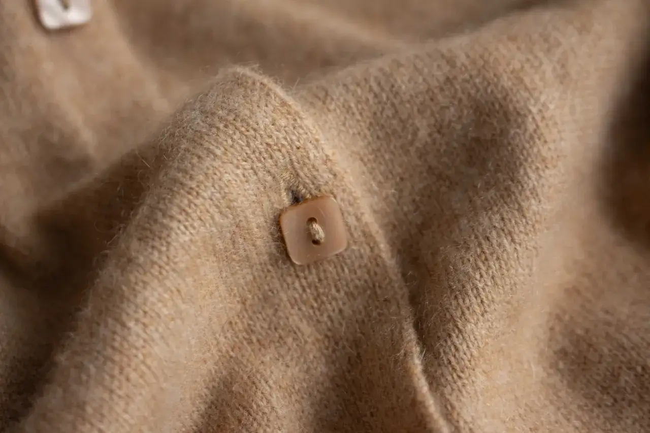 Detalle de un botón cuadrado en un suave tejido de kashmir color camel.
