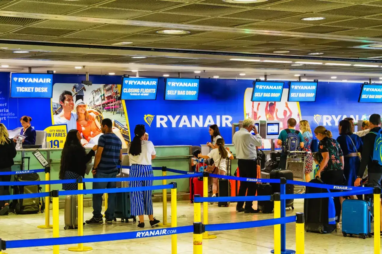 Odprawa Ryanair w tłumie pasażerów z bagażami przy stanowiskach