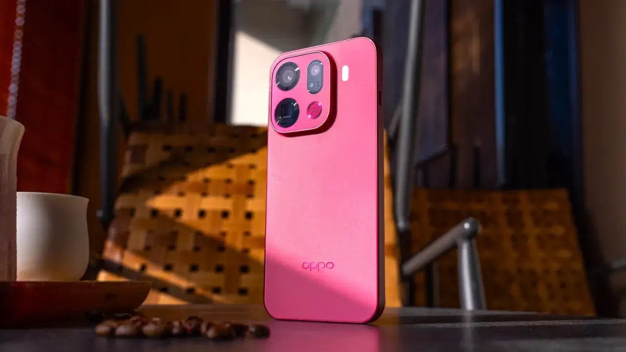 Różowy oppo flagowiec z potrójnym aparatem na tle plecionego krzesła i ziaren kawy.