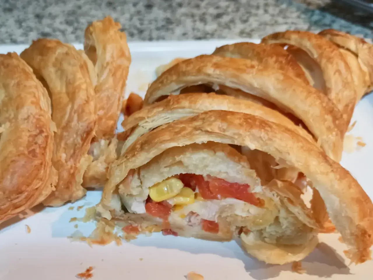 Deliciosa receta con hojaldre salado, relleno de pollo, tomate y maíz. Un bocado crujiente y sabroso.