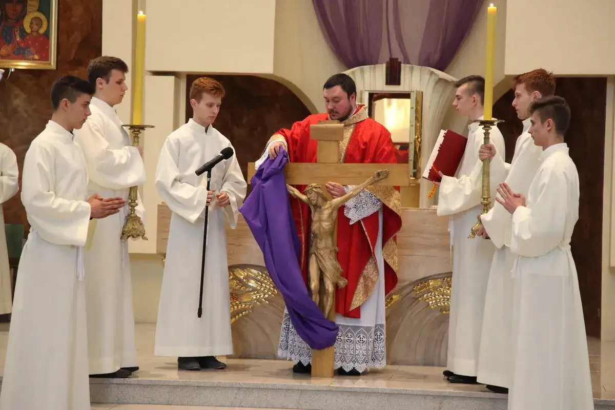 Podczas wielki piątek msza kapłan odsłania krzyż. Chłopcy w albach asystują.