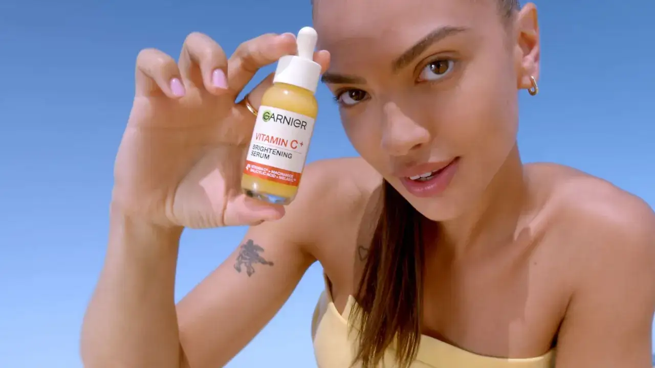 Frau mit leicht bleich im Gesicht h&auml;lt Garnier Vitamin C+ Serum.