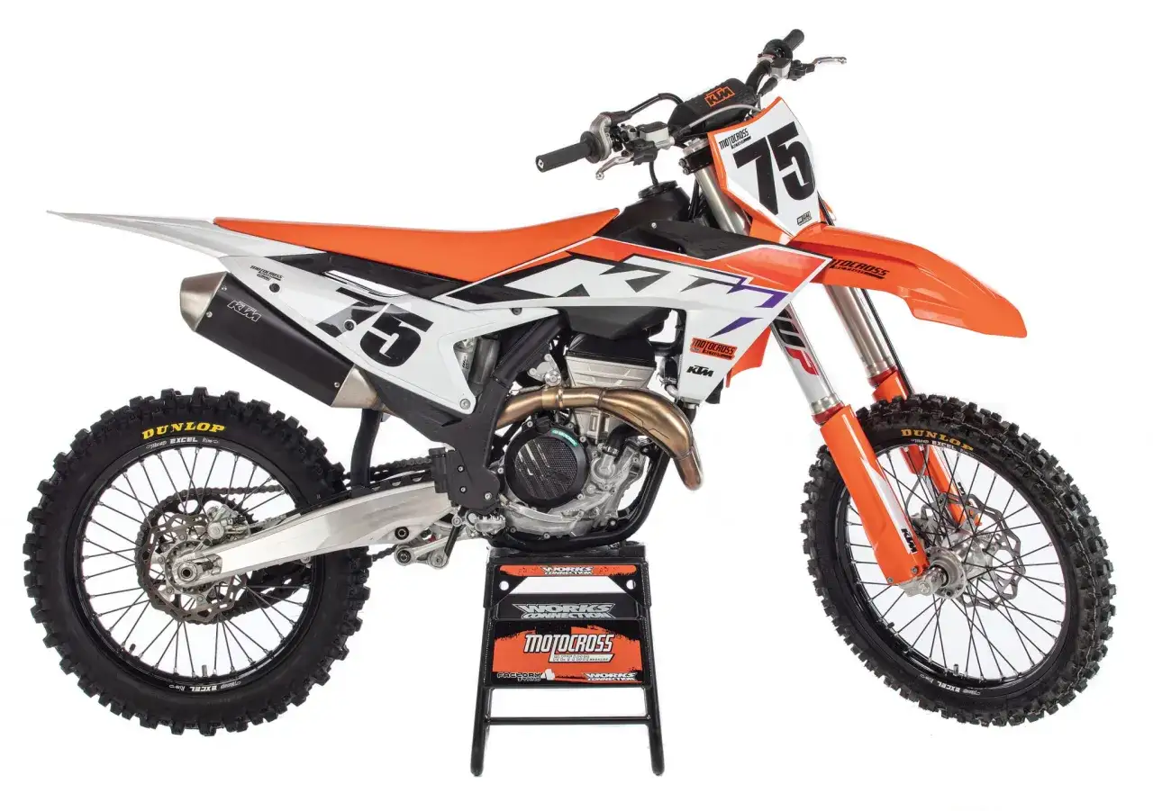 Pomarańczowo-biały motocykl KTM z numerem 75, gotowy do akcji. To nie Husqvarna, ale równie potężna maszyna do motocrossu.