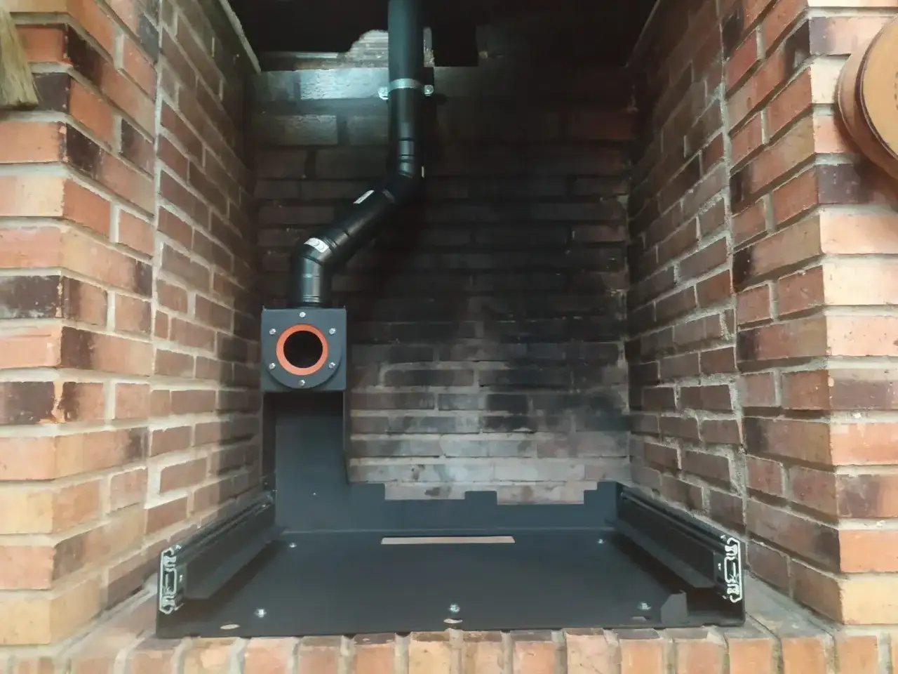 Instalación de insert pellets canalizable en chimenea de ladrillo. Sistema de extracción de humos y base metálica.