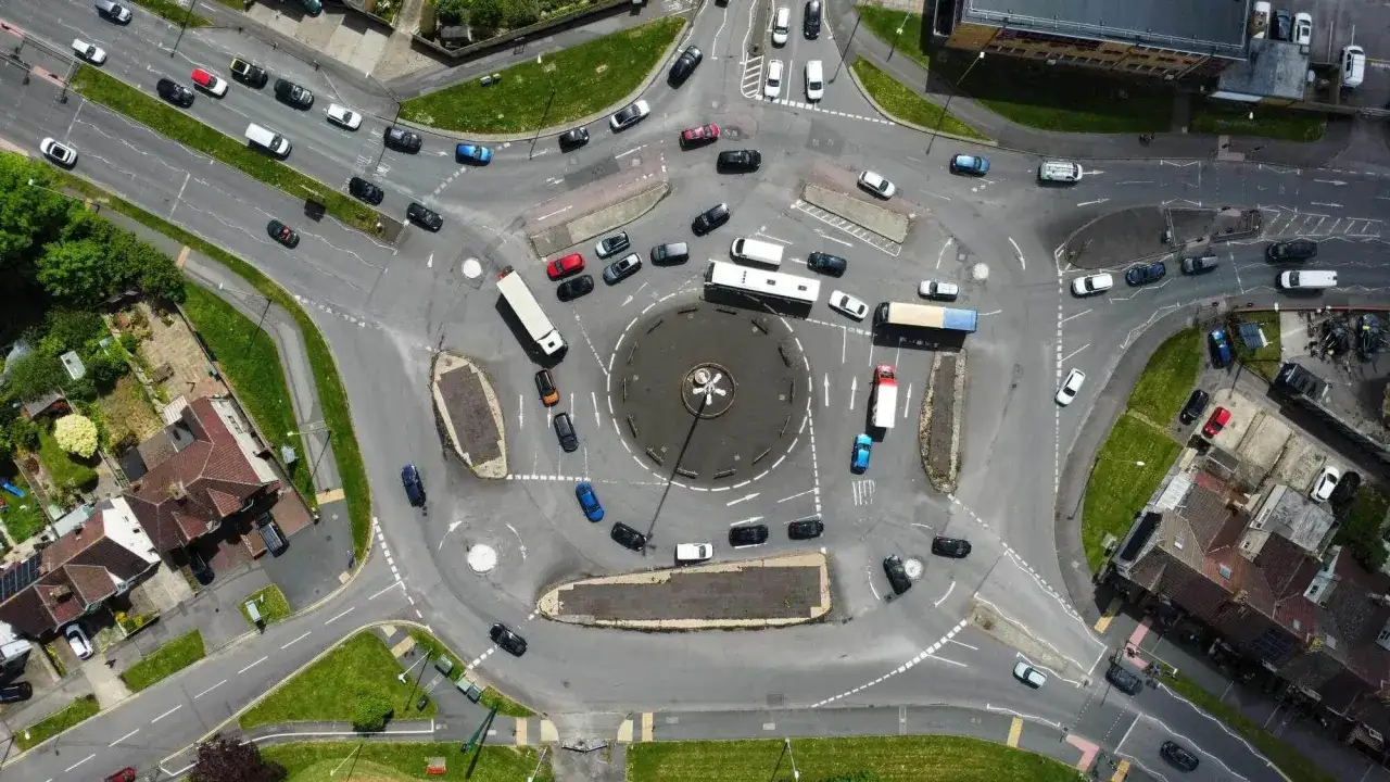 Vue aérienne d'un rond-point à 5 sorties, avec de nombreux véhicules. Apprenez comment prendre un rond-point à 5 sorties en observant le trafic.
