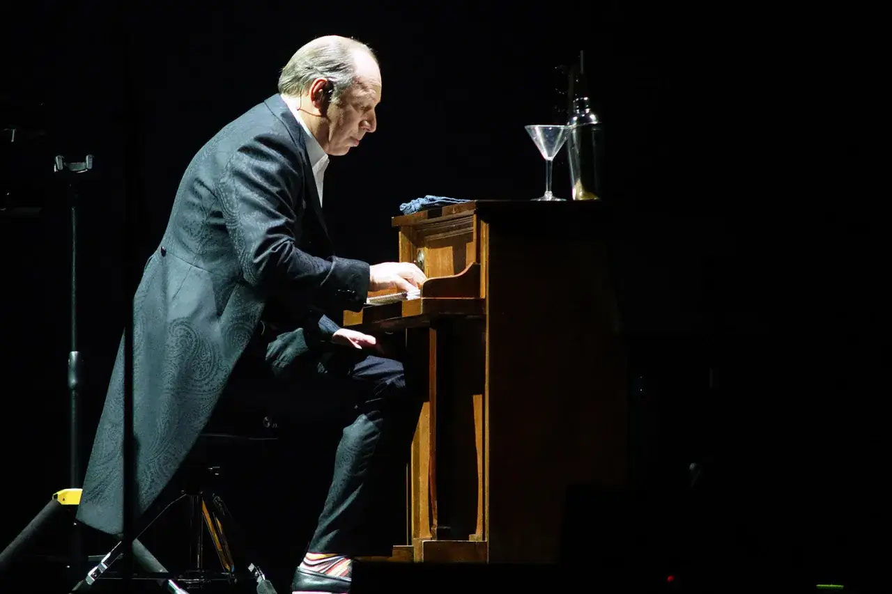 En man spelar piano på en mörk scen. Kanske komponerar han musik till nya filmer med Hans Zimmer.