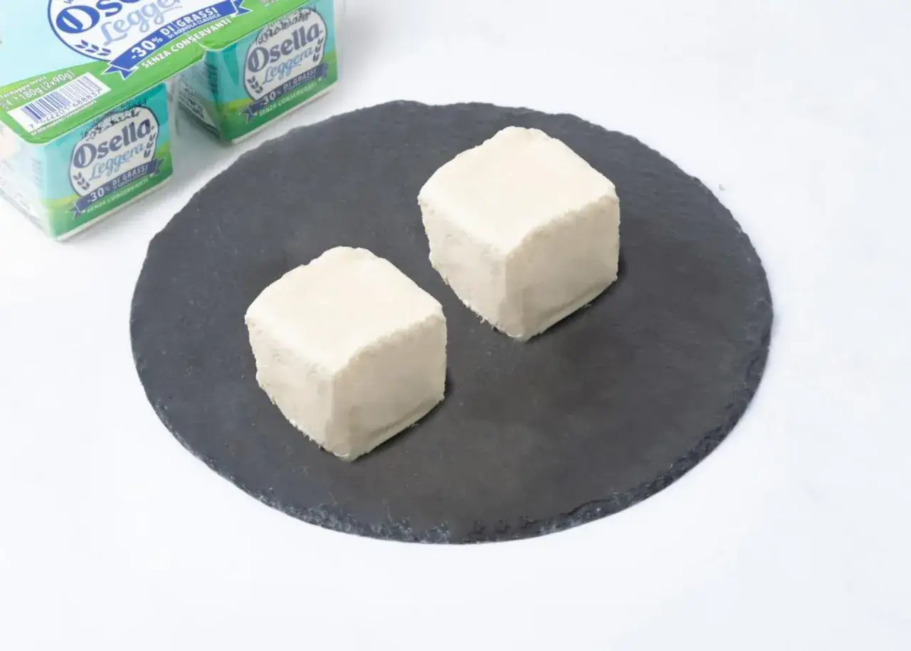 Due cubetti di robiola Osella Leggera su una pietra scura. Nonostante sia leggera, attenzione a non esagerare, perché la robiola fa ingrassare!