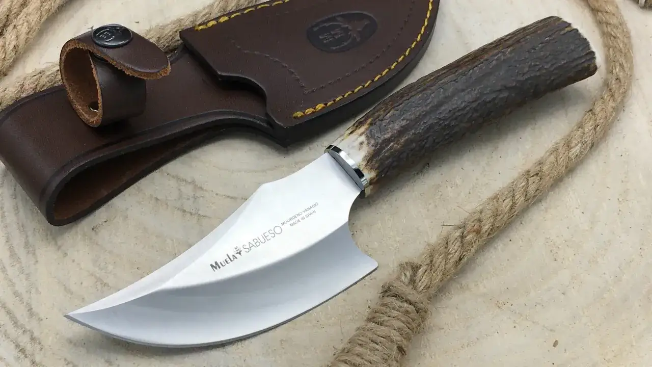 Cuchillo con mango de asta de ciervo, hoja curva y funda de cuero marr&oacute;n. La marca 