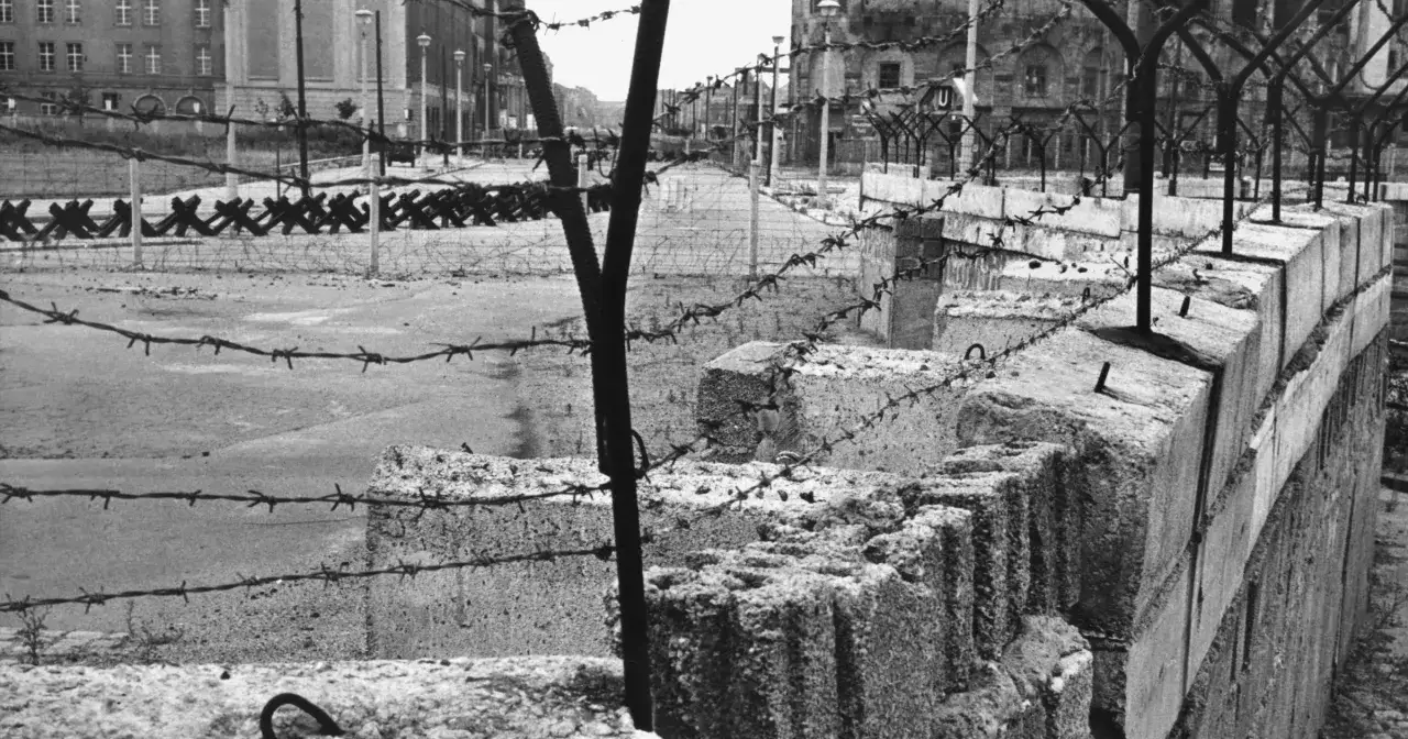 Fragment muru berlińskiego, drut kolczasty i betonowe bloki. Obraz przypomina o tym, kiedy zbudowano mur berliński.