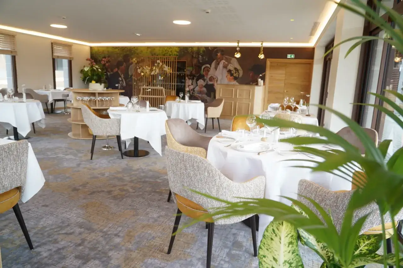 Salle &eacute;l&eacute;gante d'un restaurant &eacute;toil&eacute; &agrave; Aurillac, avec tables dress&eacute;es et fresque murale.
