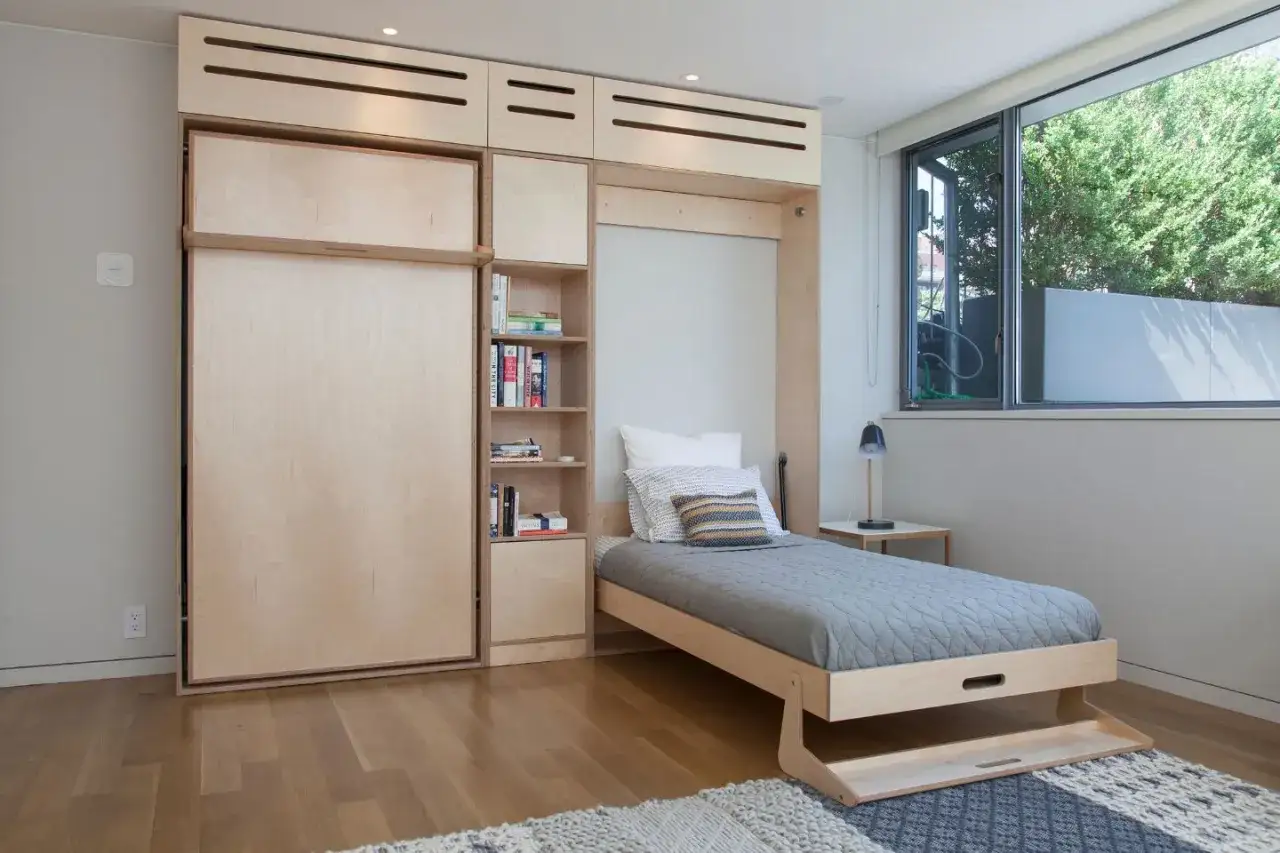 Habitación moderna con una cama nido vertical de madera, estanterías y una ventana grande.