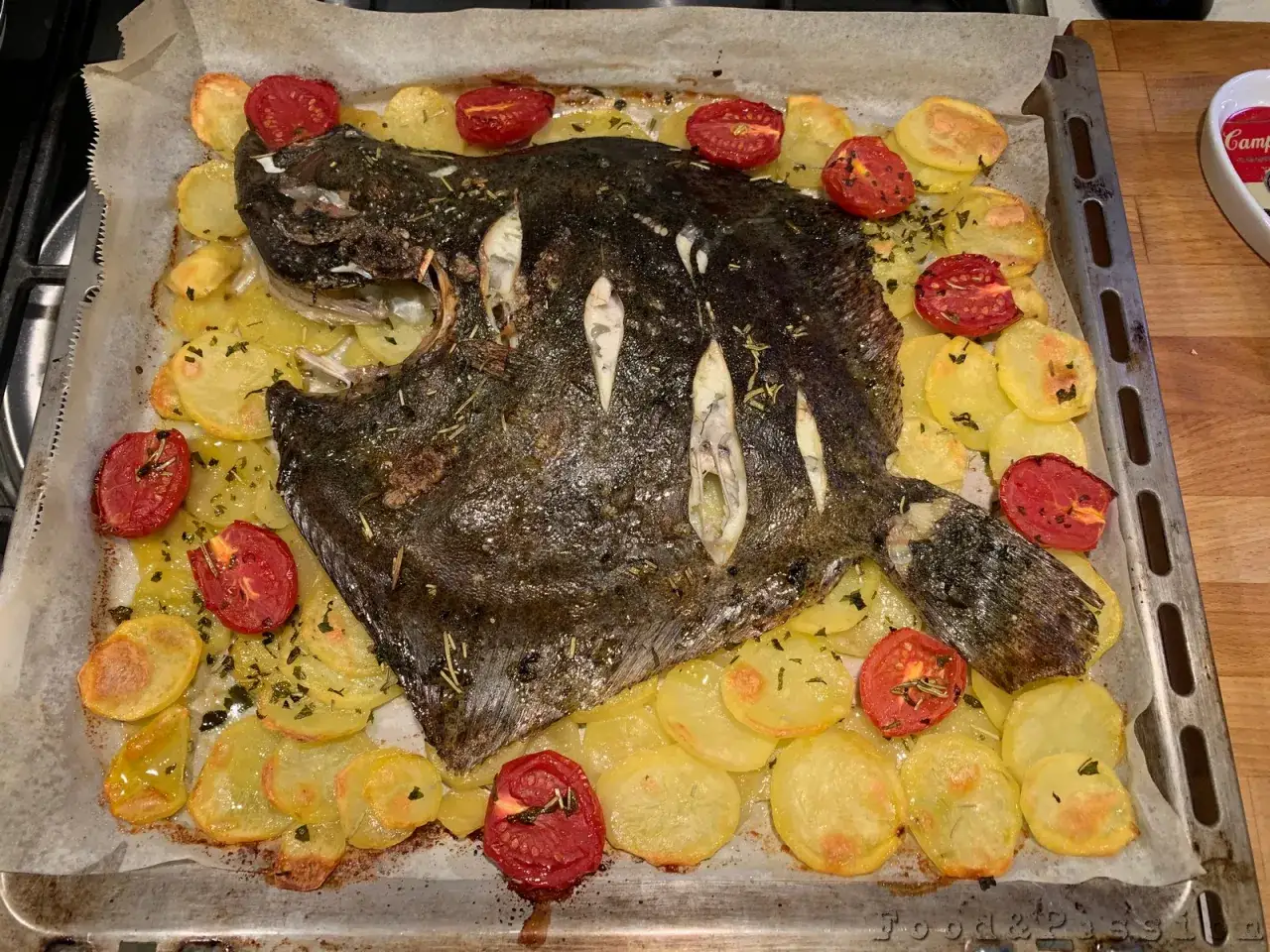 Un delizioso rombo al forno con patate e pomodorini, pronto per essere gustato.