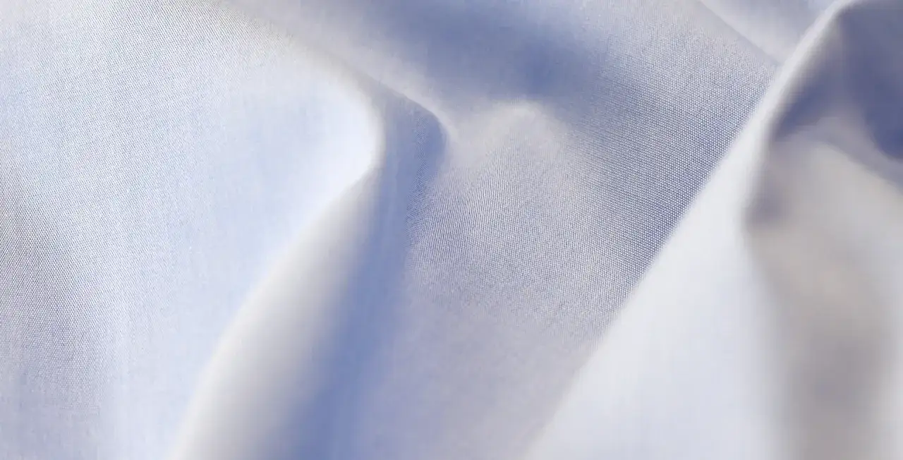 Feine, hellblaue Popeline-Webart, die sich sanft im Licht kr&auml;uselt.