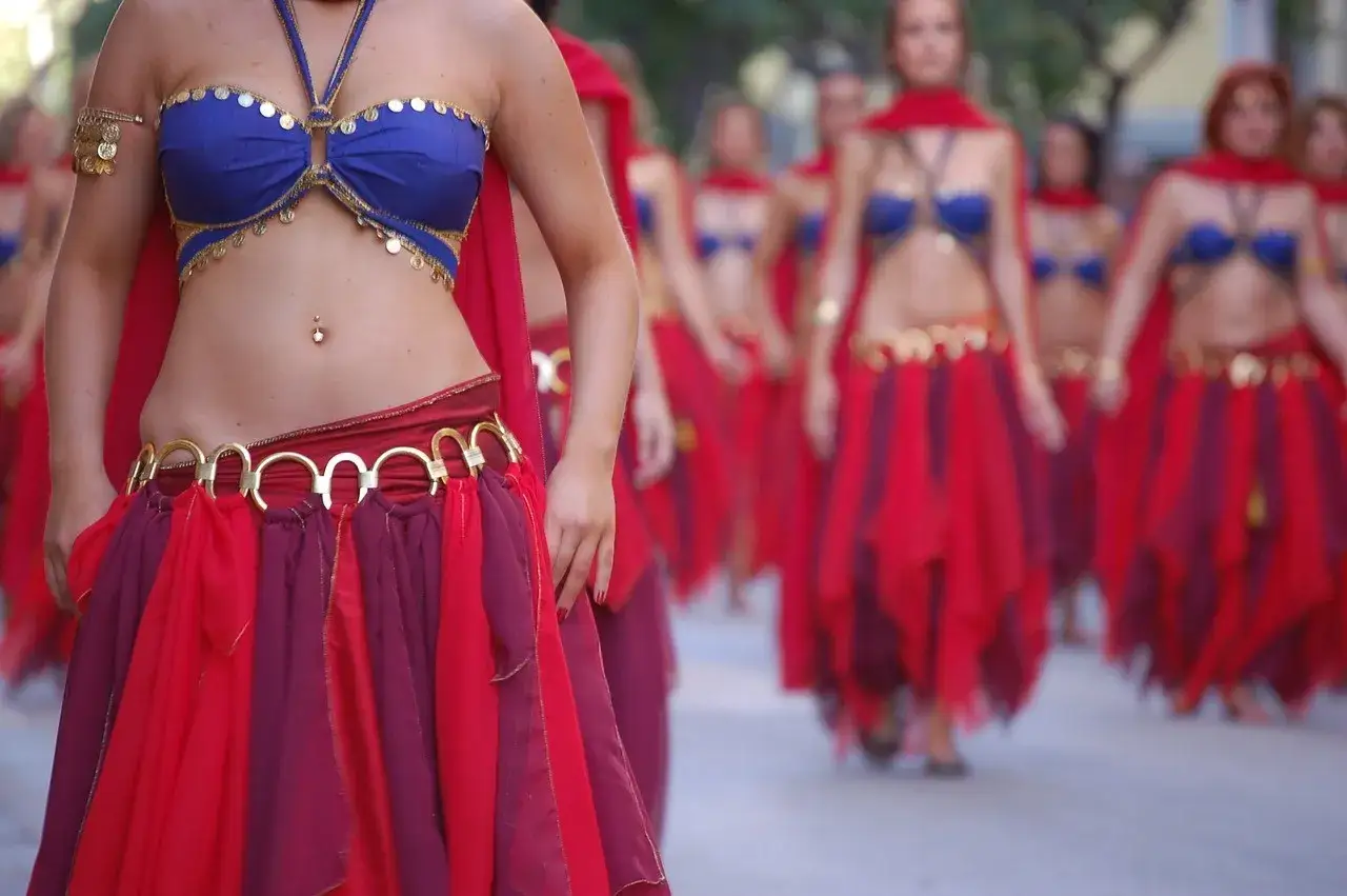 Tancerki w barwnych strojach, co to znaczy belly dance, prezentują swoje ruchy.
