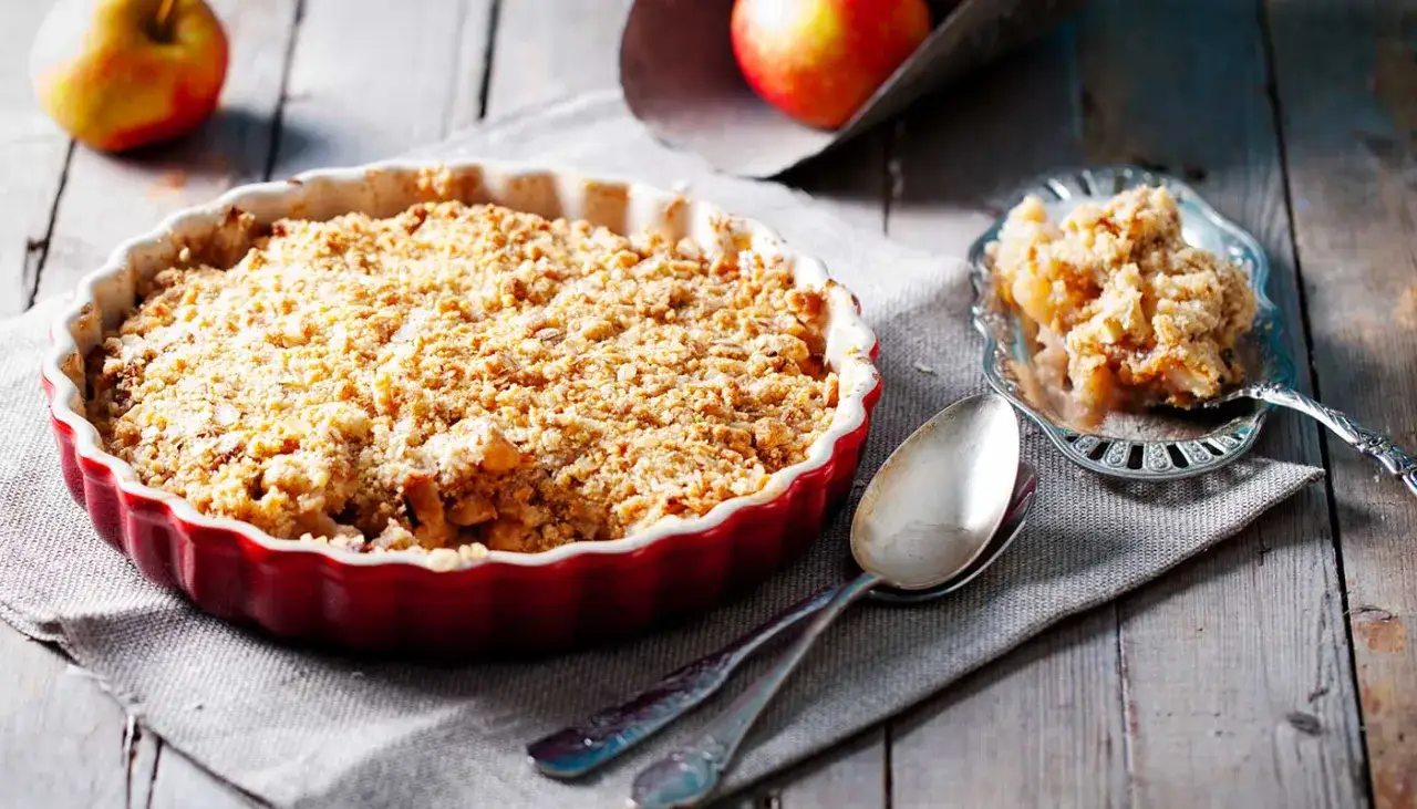 Un invitante crumble di mele appena sfornato in una teglia rossa, pronto per essere gustato.
