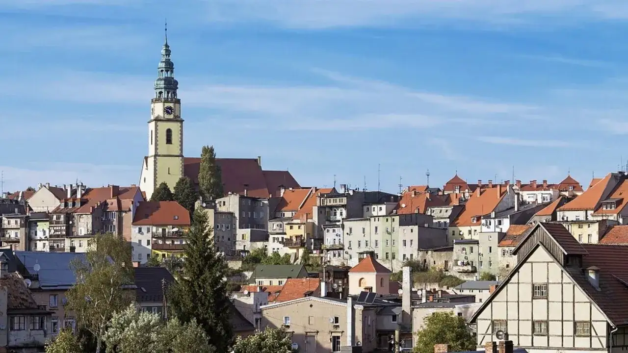 Bystrzyca Kłodzka atrakcje: malowniczy widok na miasto z wieżą kościelną i kamienicami o czerwonych dachach.