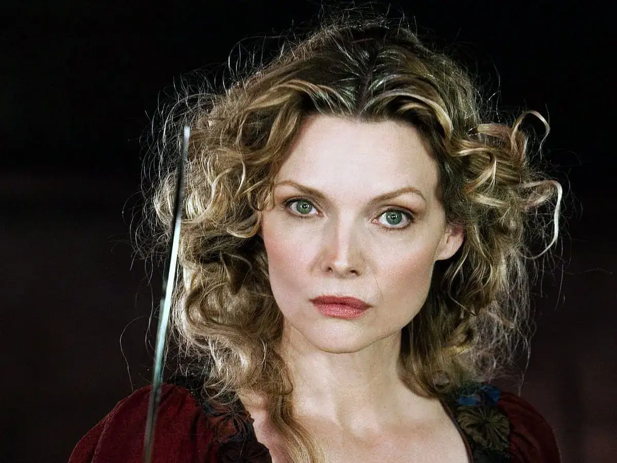Michelle Pfeiffer med lockigt hår och intensiv blick, kanske från en av hennes filmer.