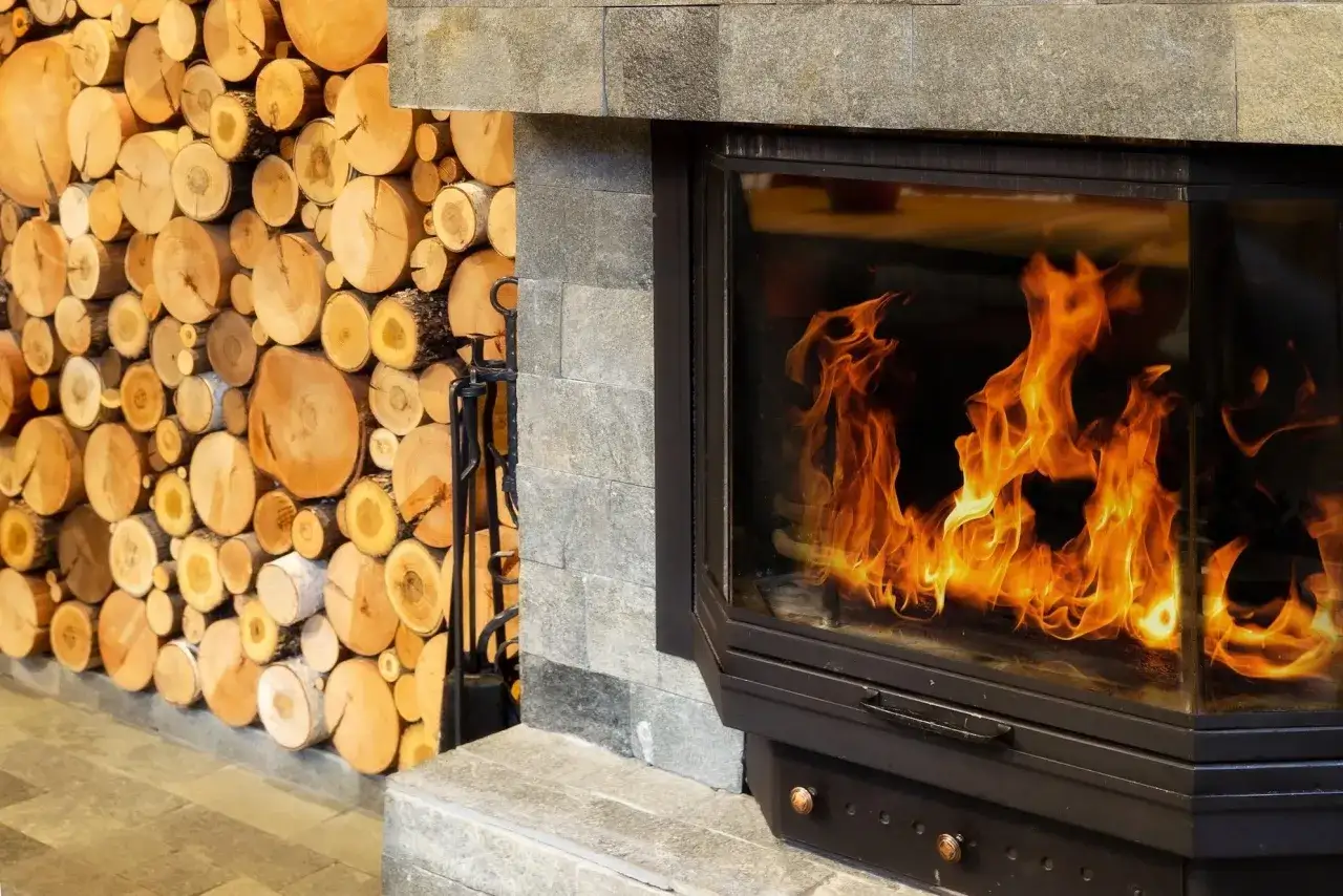 Chimenea moderna con leña apilada y fuego crepitante.