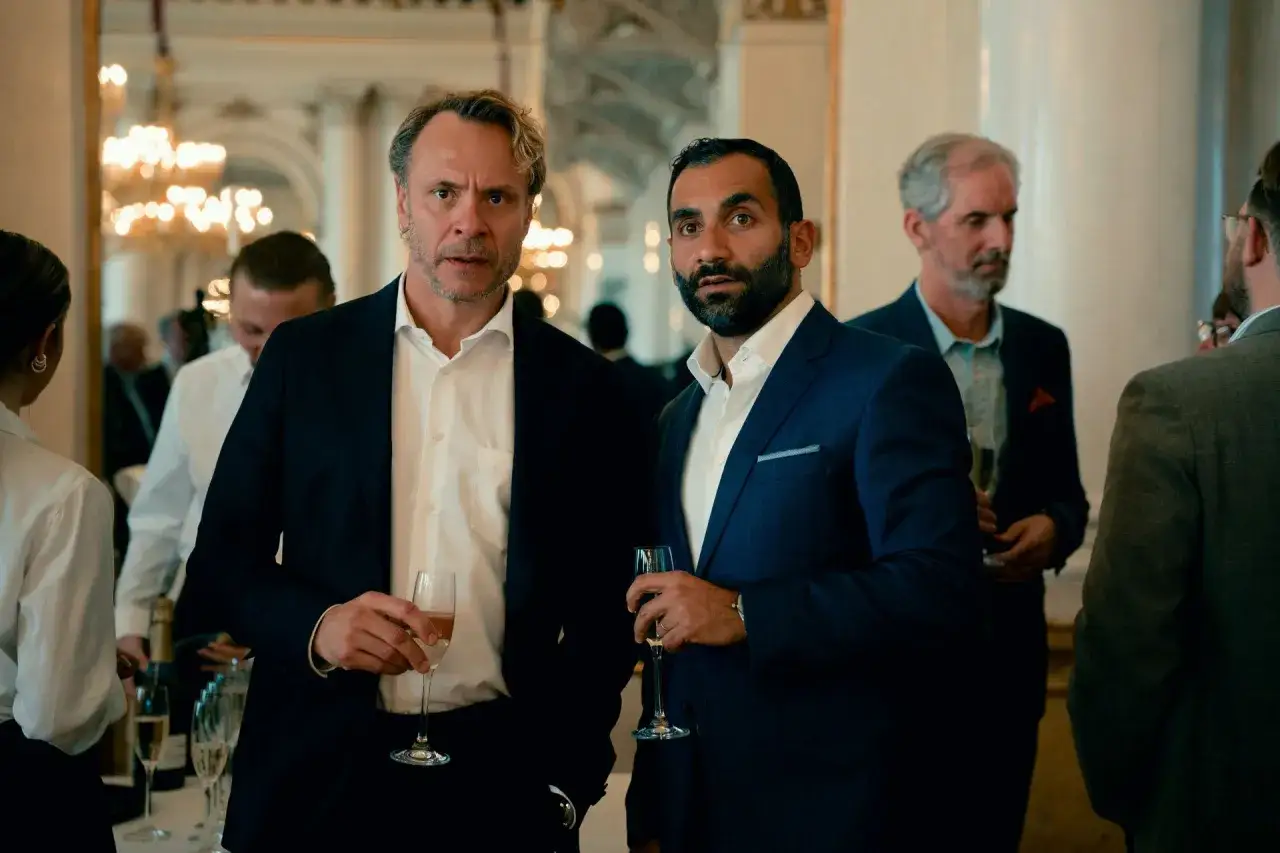 Tv&aring; m&auml;n i kostym p&aring; fest, med glas i handen. Kanske en scen fr&aring;n hundarna p&aring; SVT.