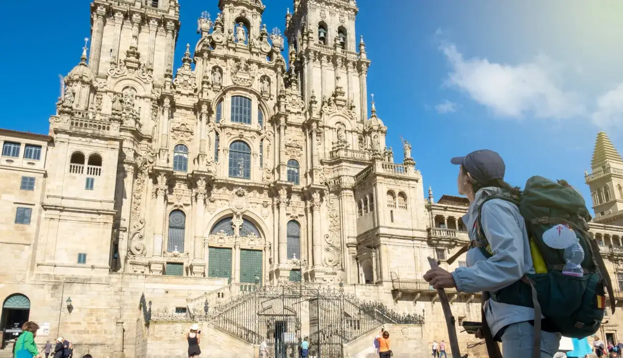 Pielgrzymka do Santiago de Compostela to coś więcej niż wycieczka krajoznawcza do kościołów. Kobieta z plecakiem przed katedrą.