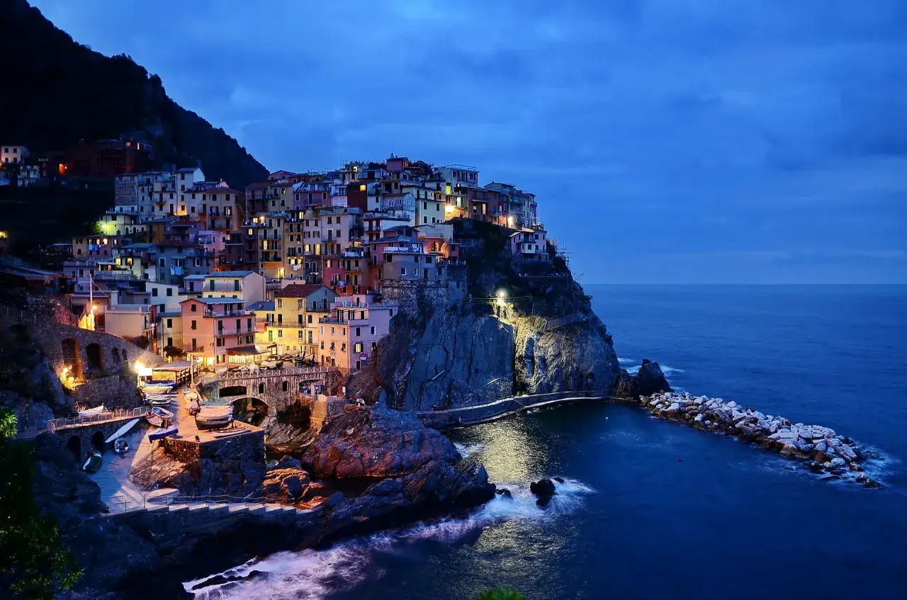 Kolorowe domy Cinque Terre na klifie, oświetlone nocą, to jedne z najpiękniejszych miejsc we Włoszech.