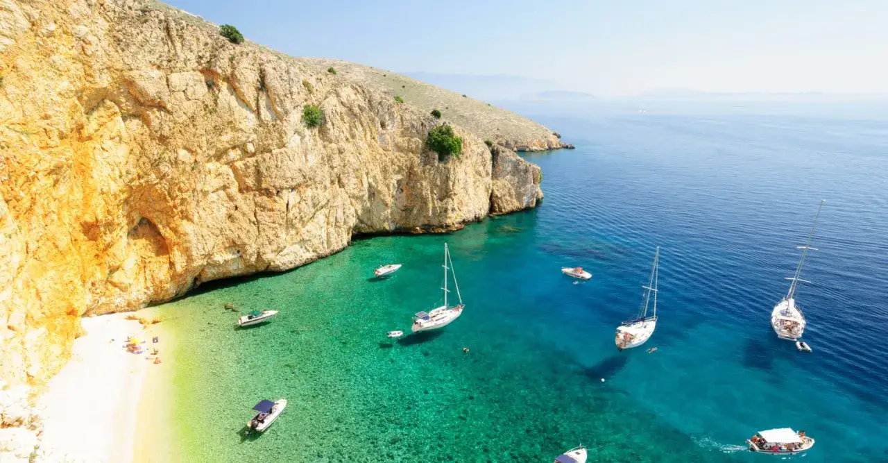 Traumhafte Bucht in der Kroatien Kvarner Bucht mit türkisfarbenem Wasser, weißen Segelbooten und einer sonnigen Kiesbucht.