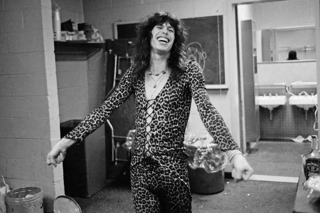 Steven Tyler młody, w panterkowym stroju, śmieje się radośnie.