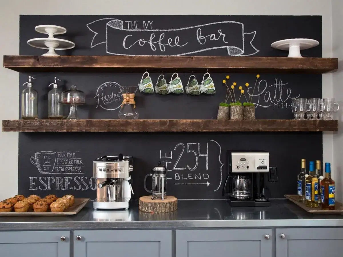 Un angolo caffè casa perfetto: macchine espresso, caffè, tazze, muffin e lavagne con scritte a mano.