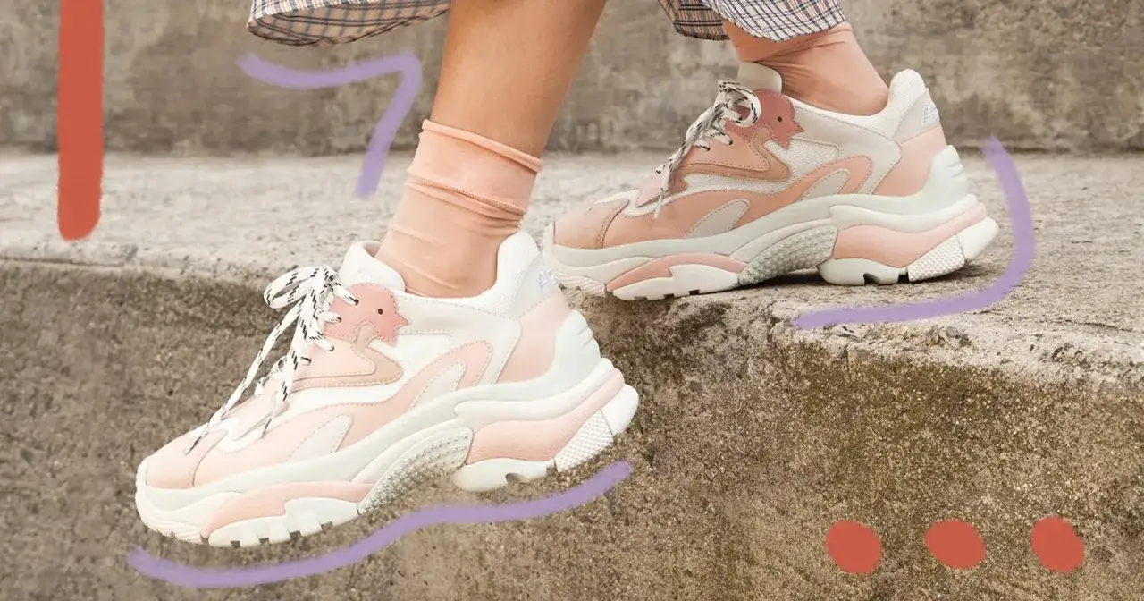 Scarpe grosse donna rosa e bianche con calzini trasparenti, su gradini di cemento.