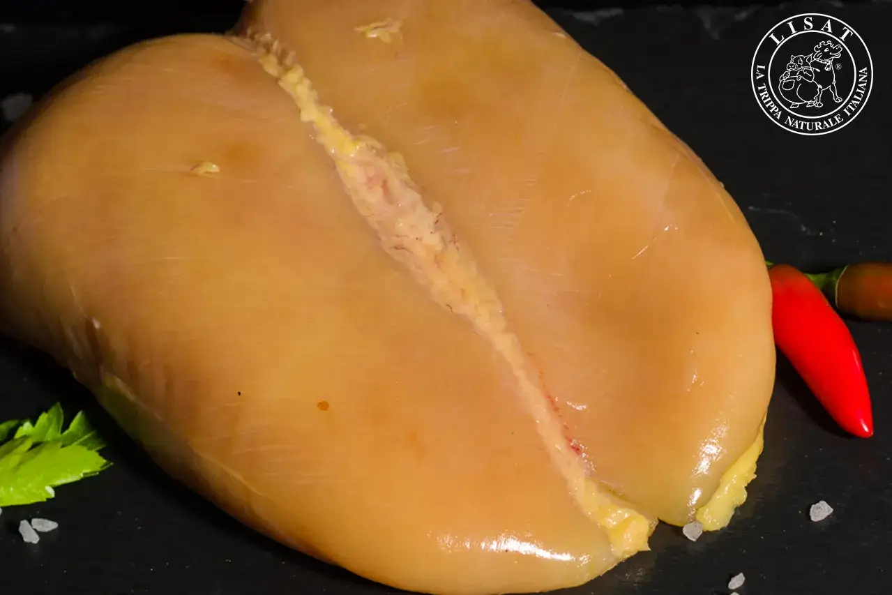 Un succulento petto di pollo dorato, pronto per essere cucinato, con peperoncino e prezzemolo a lato.