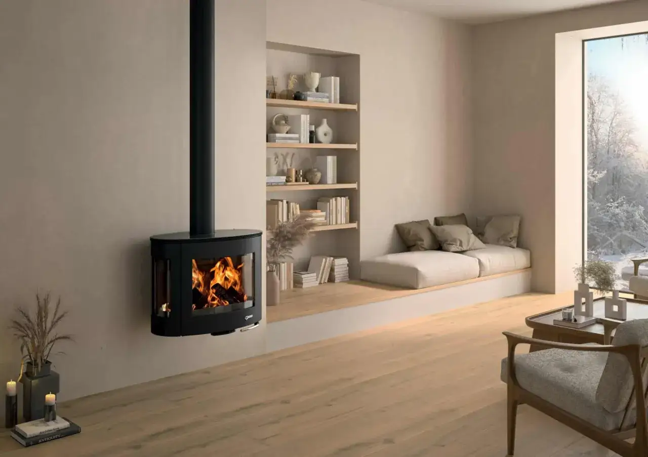 Un poêle à granulés sans ventilation, noir et suspendu, diffuse une douce chaleur dans un salon cosy. Des livres et des coussins invitent à la détente.