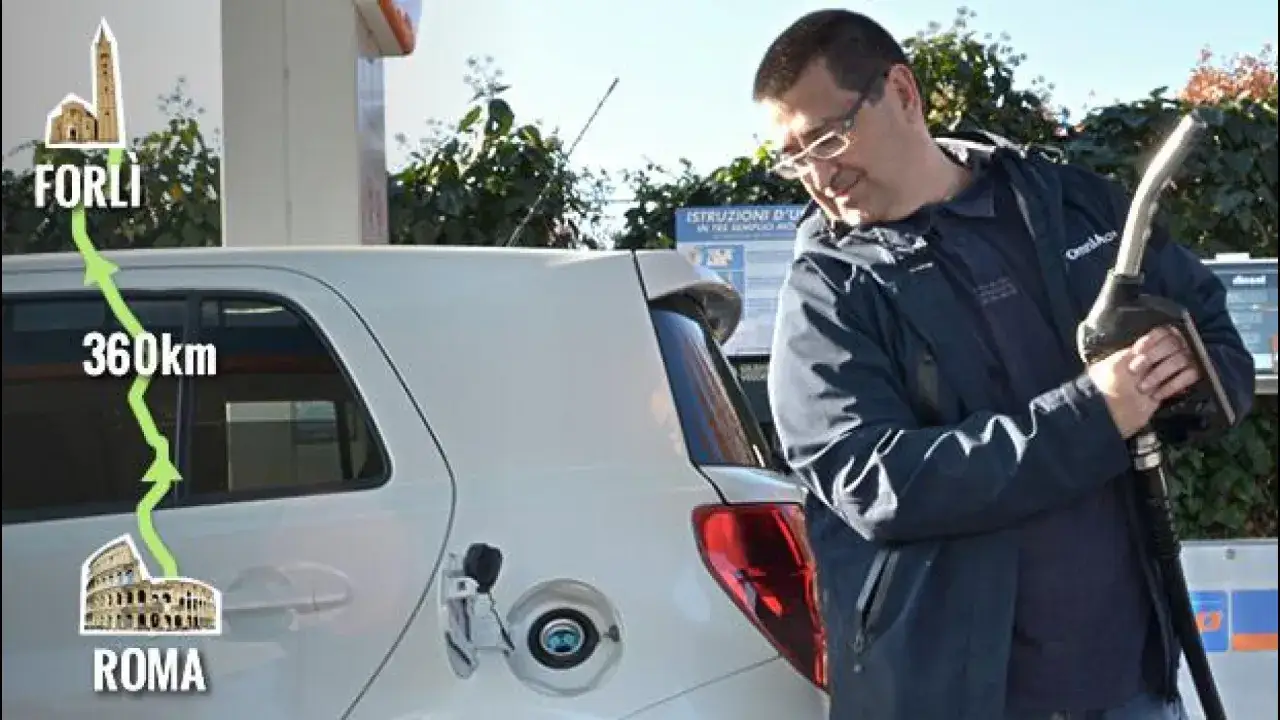 Un uomo fa rifornimento alla sua auto, pronto per un viaggio di 360 km da Roma a Forlì, mostrando i consumi reali auto.