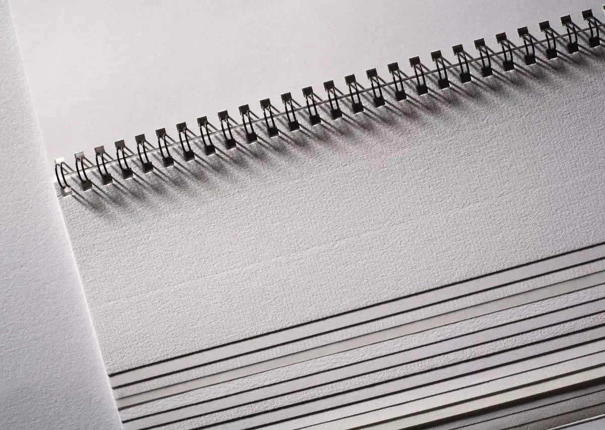 Stos papier&oacute;w o r&oacute;żnej gramaturze i grubości, połączonych spiralą. Widać, jak gramatura papieru wpływa na jego grubość.