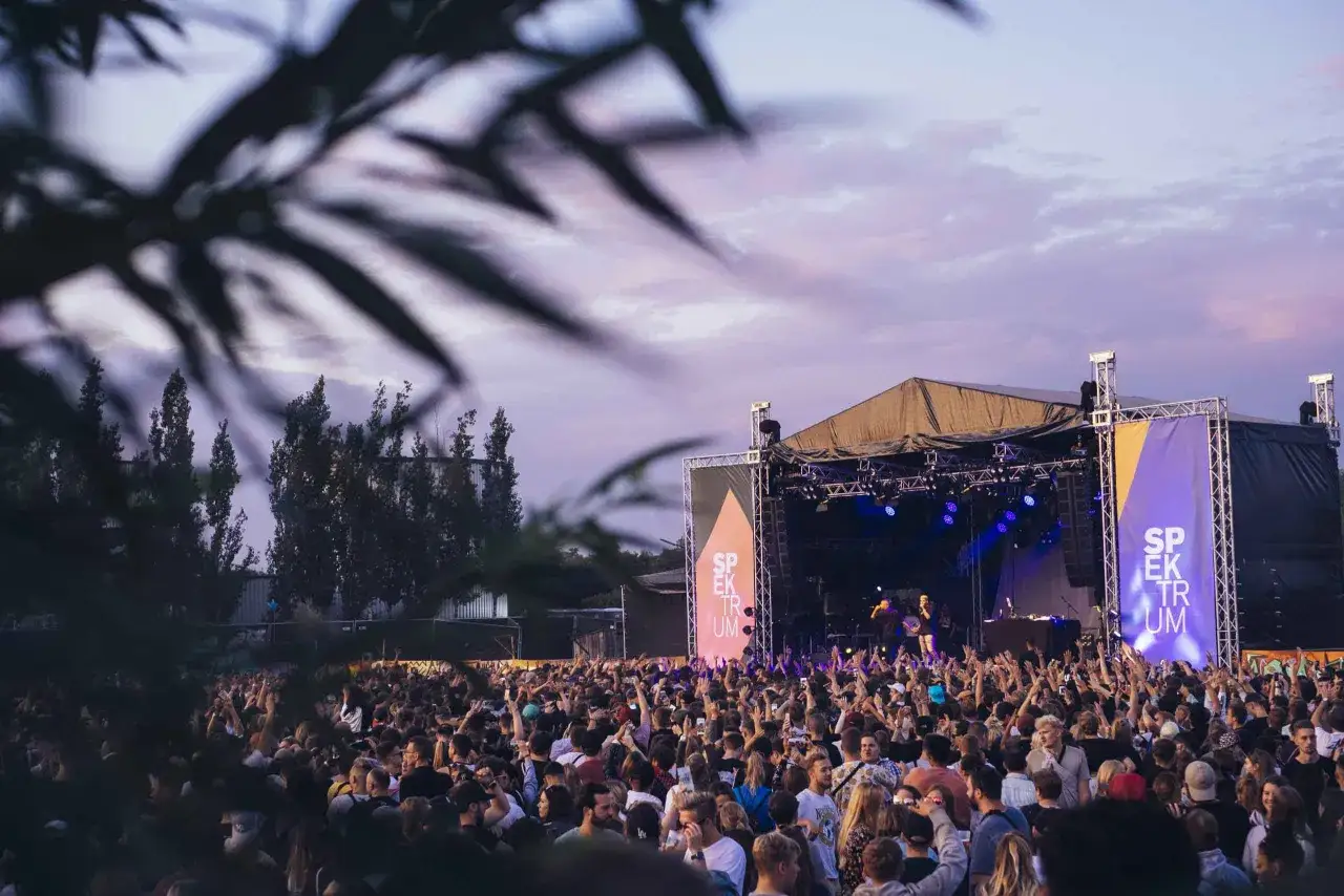 Menschenmenge feiert beim Spektrum Festival vor einer B&uuml;hne mit Lichtern und Bannern.