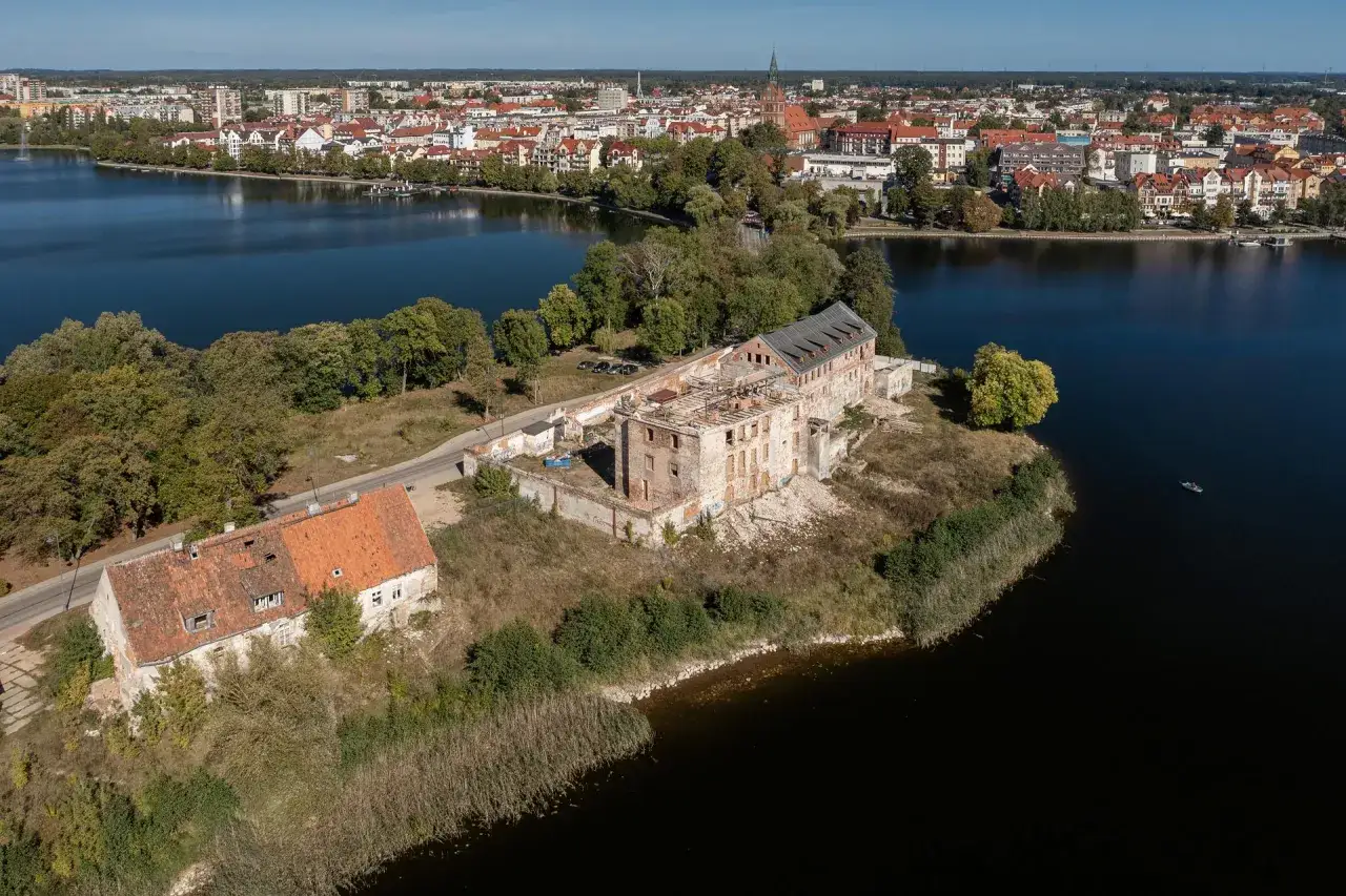 Ruiny zamku w Ełku na wyspie, z widokiem na miasto i jezioro.