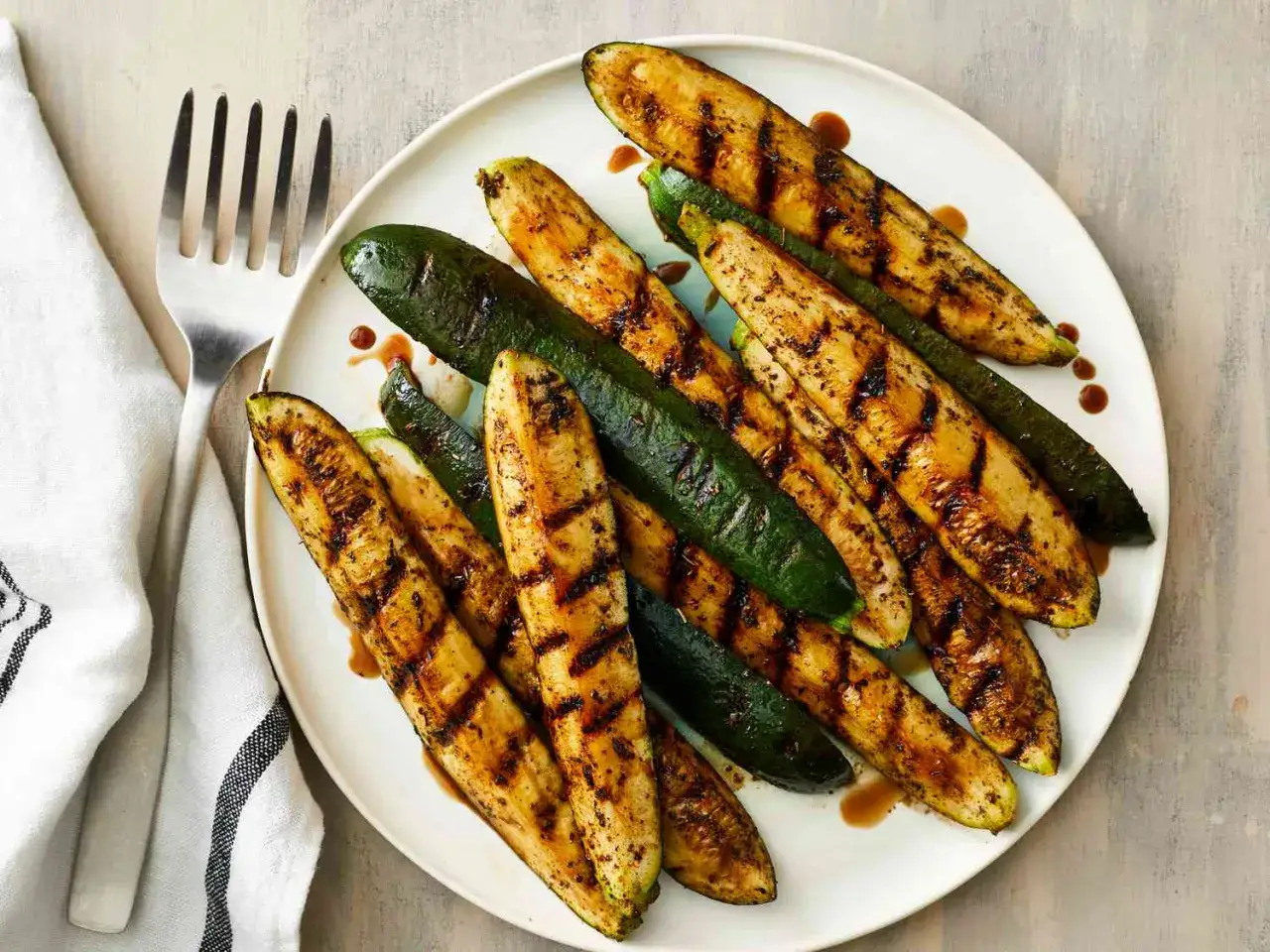 Courgettes grillées, coupées en deux, avec des marques de barbecue et un glaçage savoureux. Parfaites pour un barbecue d'été.