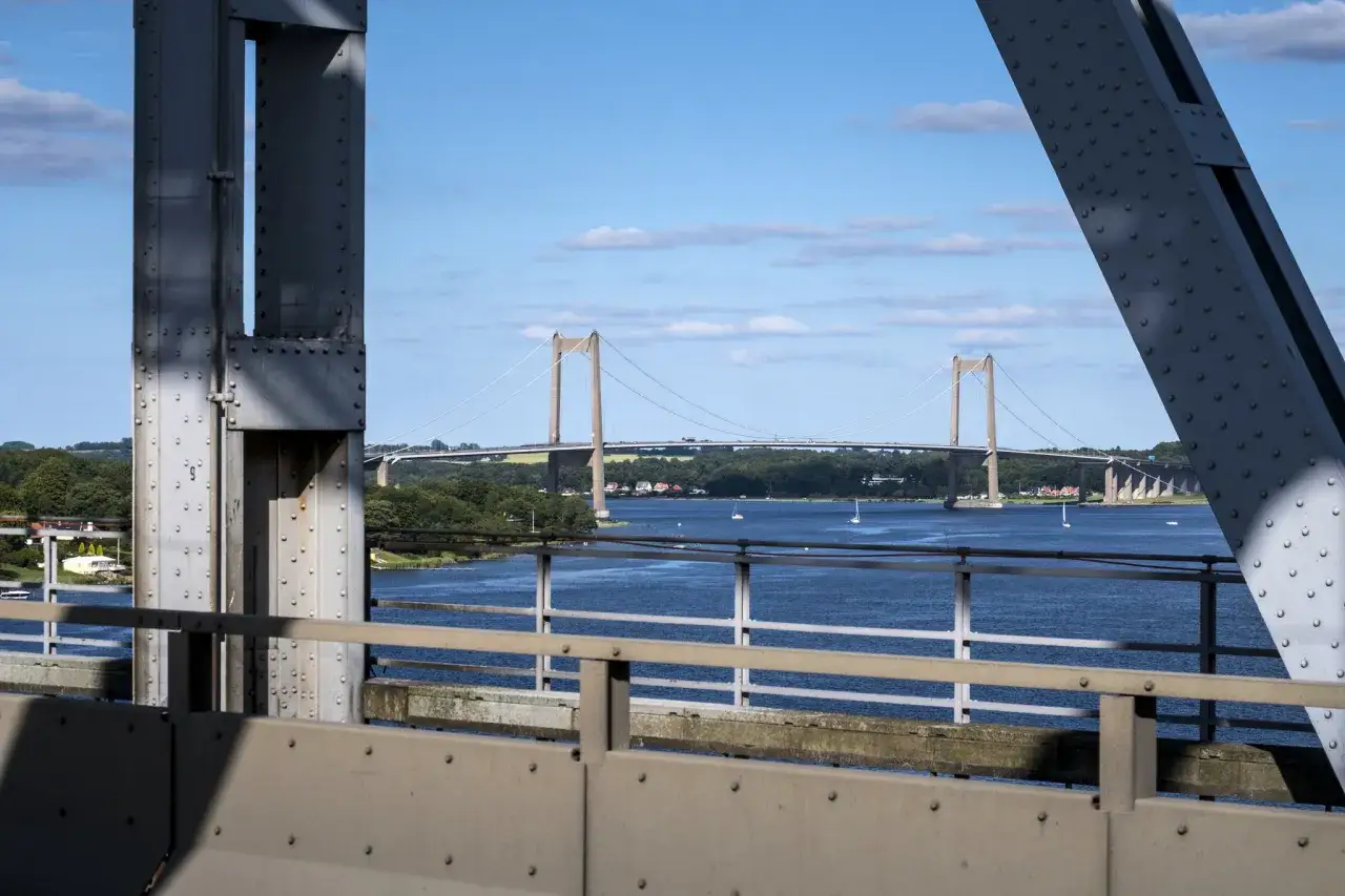 Lilla B&auml;ltbron str&auml;cker sig &ouml;ver det bl&aring; vattnet, med segelb&aring;tar som glider fram. En solig dag med moln p&aring; himlen.