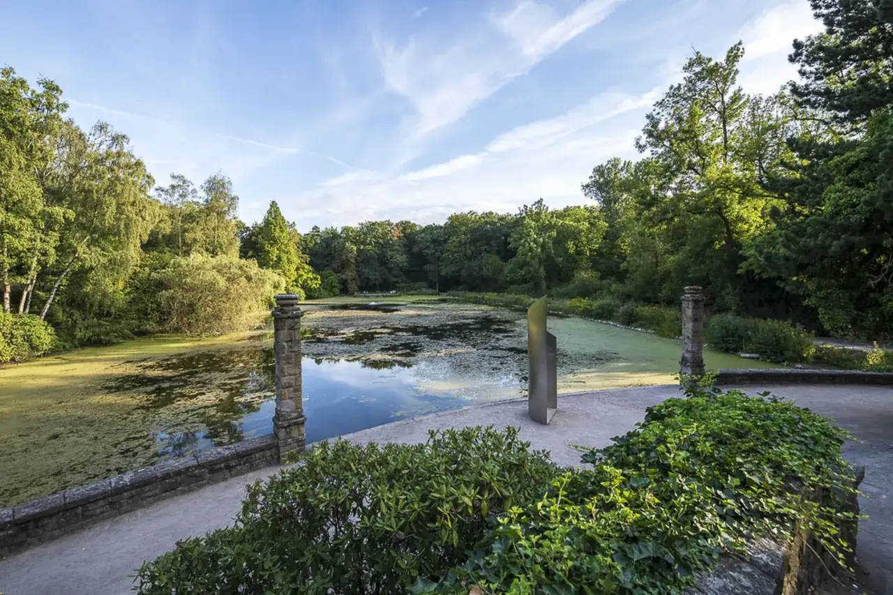 Idyllischer Teich mit Seerosen und Bäumen, ein Ort der Ruhe nahe Schloss Wittringen.