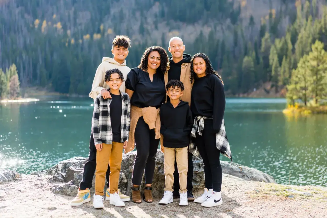 Famiglia sorridente in riva al lago. Un obiettivo 50 mm a cosa serve? Perfetto per ritratti naturali, cattura l'essenza di momenti come questo.