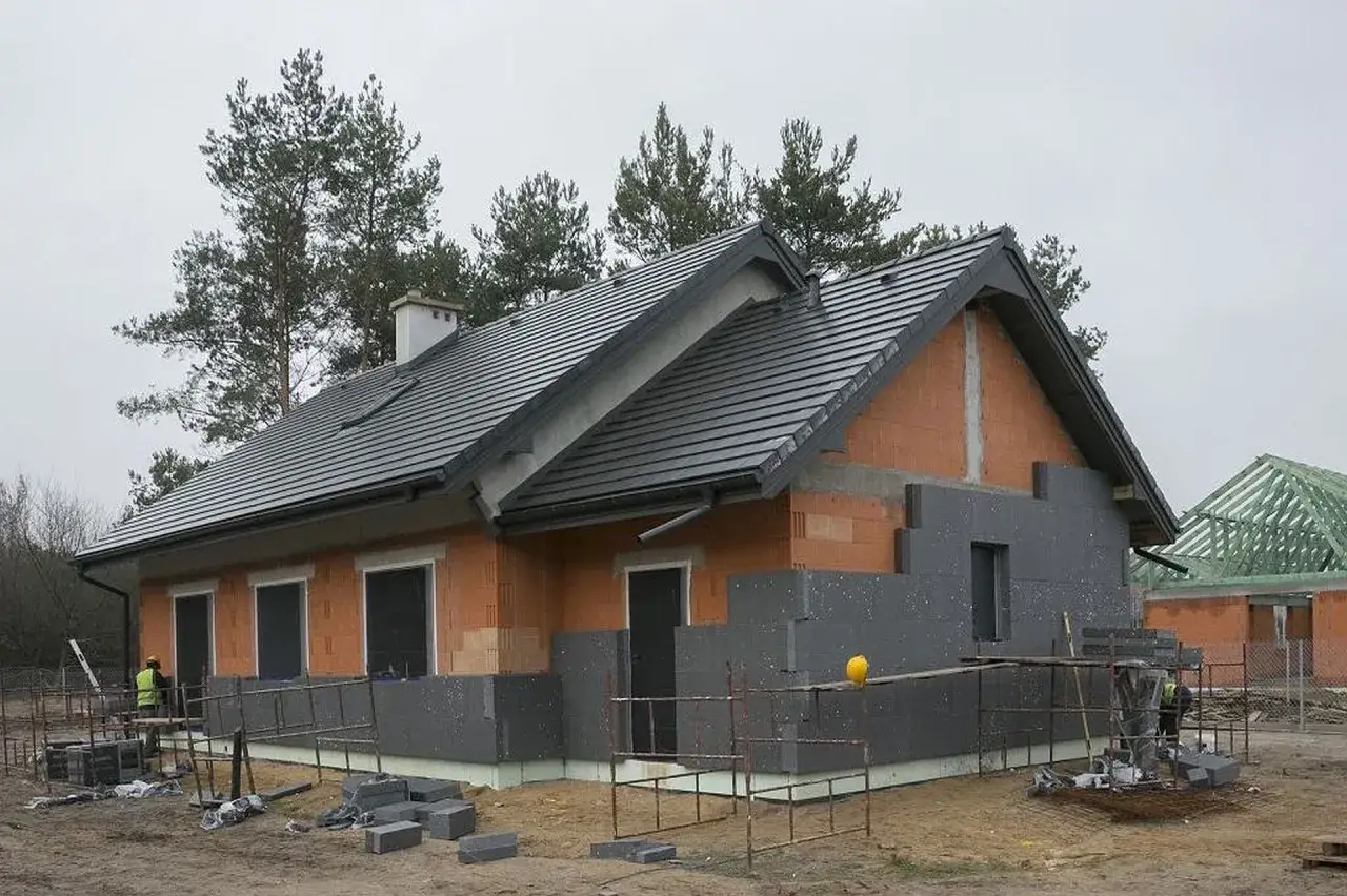 Budowa domu w toku, ściany ocieplone styropianem EPS, dach pokryty dachówką.