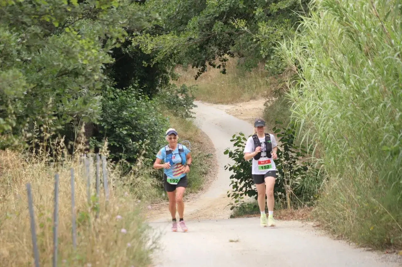 Deux coureuses s'élancent sur un chemin de terre bordé de verdure, cherchant à trouver le trail parfait pour leur course.