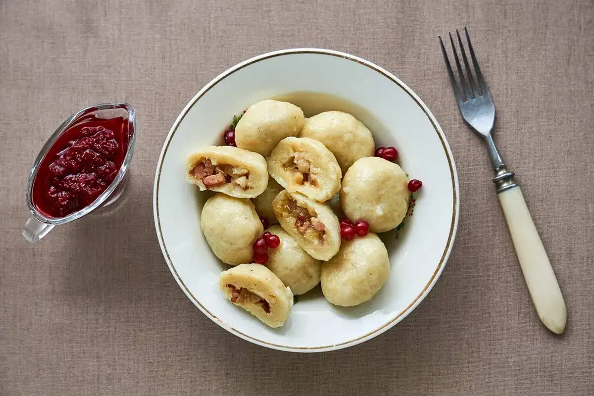 En sk&aring;l med kroppkakor, en klassisk svensk r&auml;tt, serveras med r&aring;r&ouml;rda lingon. Ett perfekt kroppkakor recept f&ouml;r en mysig middag.