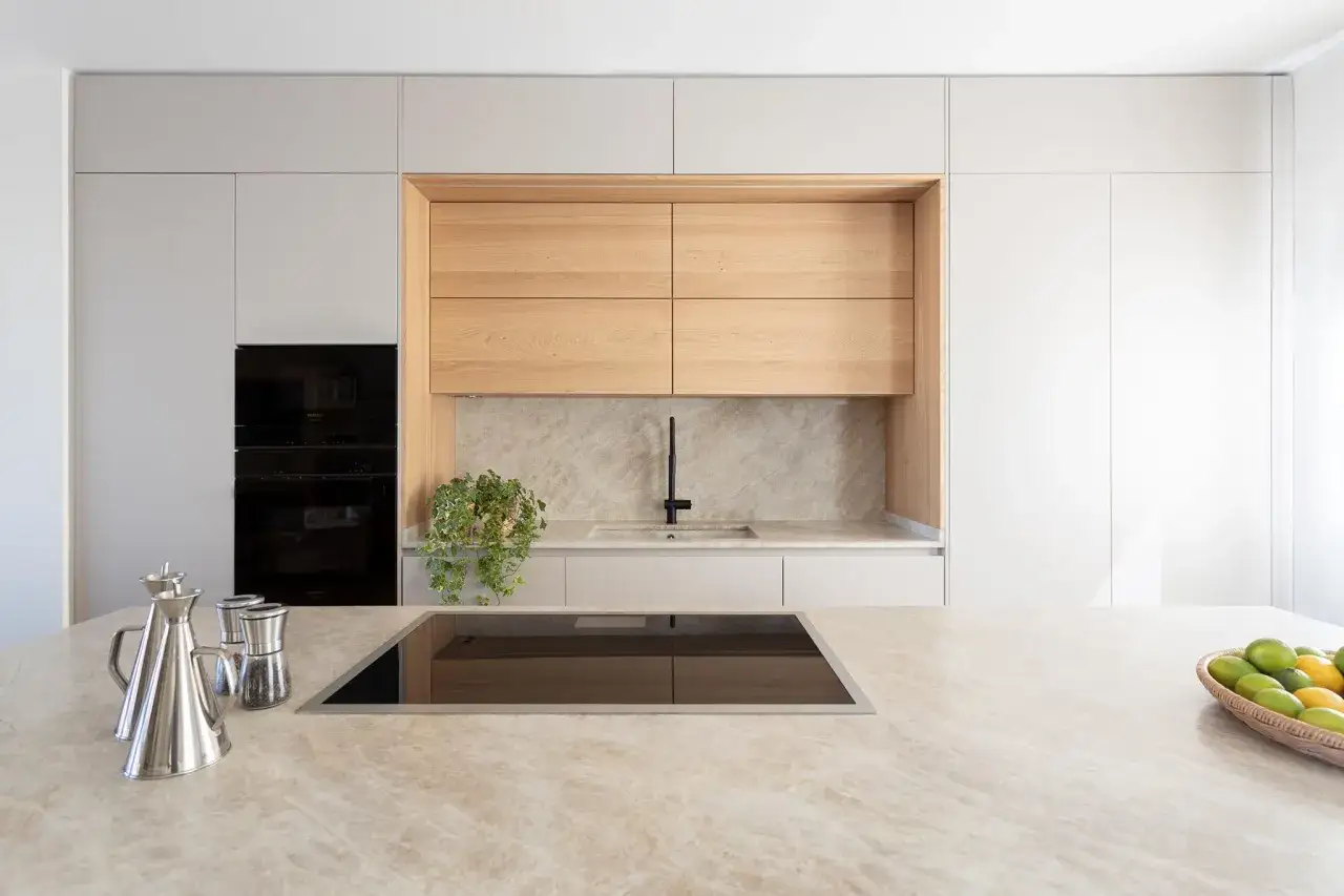 Elegante cocina con encimera de mármol y gabinetes de madera clara. La combinación de colores para cocina es moderna y acogedora.