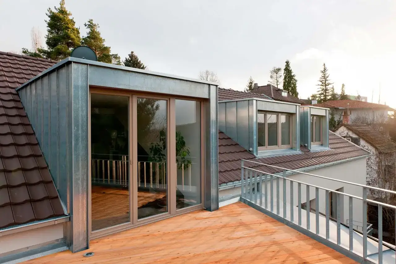 Moderner Dachausbau mit Gaube, Zinkverkleidung und großzügiger Holzterrasse.